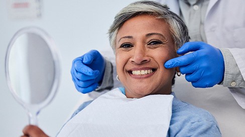 Woman smiling while holding small mirror