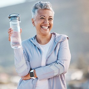 Woman smiling with water bottle on hike outside