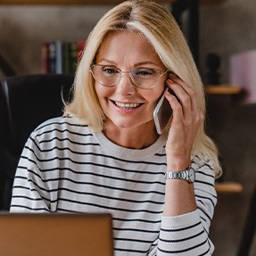 Woman with glasses smiling while talking on phone
