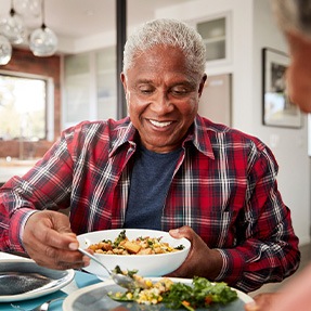 Senior man filling plate at table