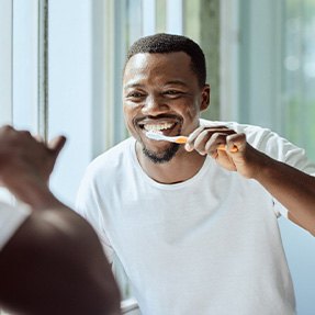 Man smiling while brushing his teeth