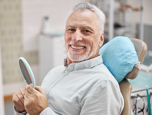 man holding mirror smiling at camera