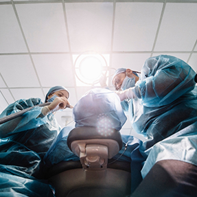 Dentist and assistant performing dental implant surgery