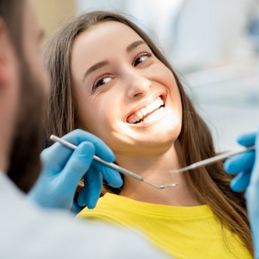 female patient smiling over at dentist