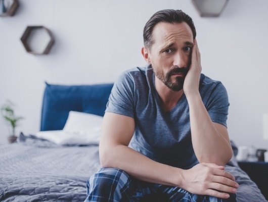 man sitting on bed upset