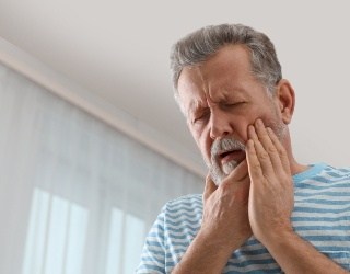 man holding jaw and cheek