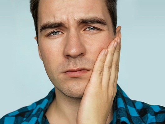 close up of man holding cheek