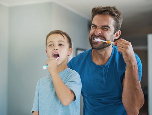 a father and son brushing their teeth