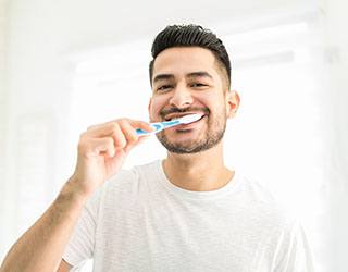 person brushing their teeth and smiling