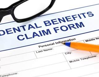 Dental implant benefits form with glasses and pen