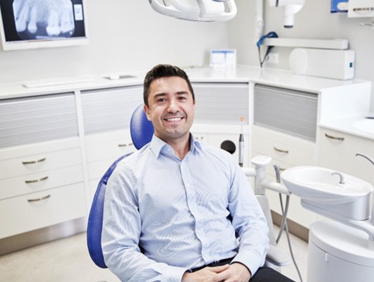 Male patient smiling and waiting in dental chair