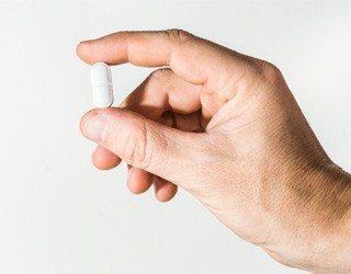 Close-up of hand holding a single painkiller pill