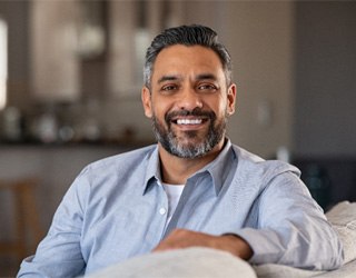 Bearded man smiling and sitting on his couch