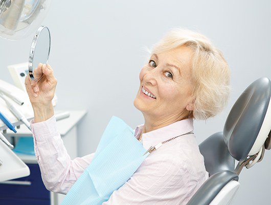 woman holding mirror up smiling