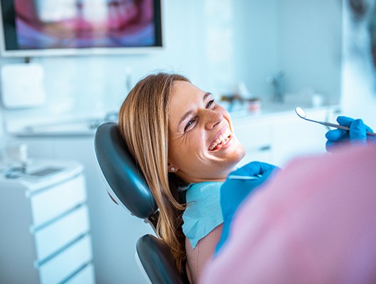 Woman smiling at dentist while sitting in treatment chair