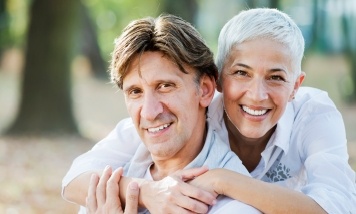 woman hugging husband from behind and smiling