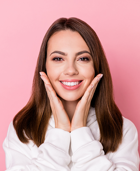 Smiling woman touching her face after teeth whitening in Coral Springs