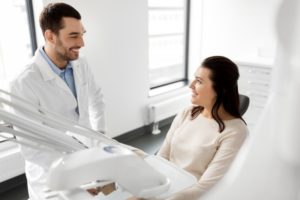 Female patient in dental chair smiling with male dentist