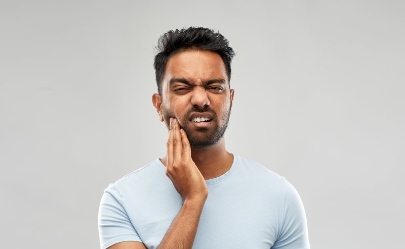 Man holding his jaw with his face scrunched up in pain